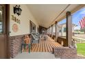 Inviting covered porch with brick accents, outdoor seating and a view of the front yard at 1851 E 138Th Ave, Brighton, CO 80602