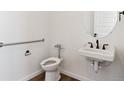Compact bathroom featuring a toilet, a small sink, modern fixtures, and accessibility bar at 11487 E Briarwood Cir, Centennial, CO 80112