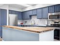 Kitchen with stainless steel appliances, wood countertop on the breakfast bar and blue cabinets at 4301 S Pierce St # 6D, Littleton, CO 80123