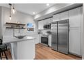 Bright kitchen features white cabinets, stainless steel appliances, light countertops, and wood flooring at 2140 S Ash St # 102, Denver, CO 80222