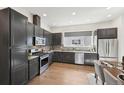 Modern kitchen with dark cabinetry, stainless steel appliances, and hardwood floors at 7812 W 43Rd Pl, Wheat Ridge, CO 80033