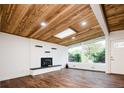 Sun-filled living room features a modern brick fireplace, stylish wood floors, and a striking wood ceiling with a skylight at 7695 Quitman St, Westminster, CO 80030