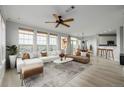 Bright living room with a ceiling fan, expansive windows, and a stylish rug adjacent to the open concept kitchen at 13456 Via Varra # 401, Broomfield, CO 80020