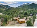 Scenic aerial view showcasing the house nestled among towering trees and majestic mountain landscapes at 11398 Ranch Elsie Rd, Golden, CO 80403