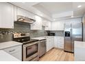 Modern kitchen featuring stainless steel appliances, white cabinets, and tile backsplash at 13952 E Marina Dr # 310, Aurora, CO 80014