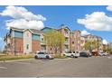 A wide angle view of a brick apartment complex showcasing ample parking and manicured landscaping at 2662 S Cathay Way # 302, Aurora, CO 80013