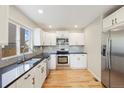 Modern kitchen with white cabinets, stainless steel appliances, granite countertops, and light-colored hardwood floors at 777 Whispering Oak Dr, Castle Rock, CO 80104