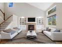 Bright living room with vaulted ceiling, built-in shelving, a fireplace, and large windows providing ample natural light at 777 Whispering Oak Dr, Castle Rock, CO 80104
