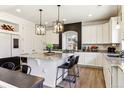 Bright kitchen featuring white cabinets, granite countertops, modern light fixtures, and a kitchen island with seating at 4736 S Buchanan St, Aurora, CO 80016