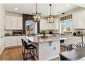 Bright kitchen featuring white cabinets, granite countertops, modern light fixtures, and a kitchen island with seating at 4736 S Buchanan St, Aurora, CO 80016