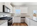 Bright kitchen features granite countertops, stainless steel appliances and wood floor at 7306 Arkansas St, Frederick, CO 80530