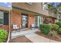Inviting brick porch with seating, creating a welcoming entrance with mature landscaping at 8981 E Amherst Dr # E, Denver, CO 80231