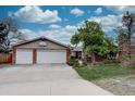 Inviting front exterior features a brick facade, double garage, basketball hoop and mature trees at 13959 W Cedar Pl, Golden, CO 80401