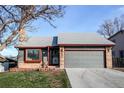 Inviting home exterior featuring a two-car garage, brick accents, and tidy landscaping at 18874 E Mexico Dr, Aurora, CO 80017