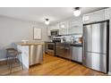 Modern kitchen with stainless steel appliances, white cabinets, and a butcher block island with seating at 75 N Emerson St # 104, Denver, CO 80218
