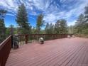 Expansive wooden deck featuring charming wood carvings, lovely flower arrangements, and wooded scenery at 11608 Apache Trl, Conifer, CO 80433