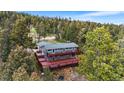 Aerial view of a multi-level home nestled in the trees with an expansive wrap-around deck, perfect for outdoor living at 11608 Apache Trl, Conifer, CO 80433