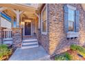 Close up on the covered front porch of this stone accented home and its stylish entrance at 12059 S Tallkid Ct, Parker, CO 80138