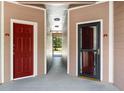 Hallway featuring two red apartment doors and a view of trees at 7440 S Blackhawk St # 2-104, Englewood, CO 80112