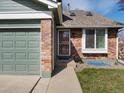 Close-up of home's exterior featuring brick accents, a storm door, and well-maintained lawn at 5557 S Simms Way, Littleton, CO 80127