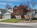Two-story home with a two-car garage, brick accents, and mature trees on a corner lot with blue skies at 5557 S Simms Way, Littleton, CO 80127