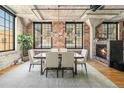 Open dining area features brick accent wall, fireplace, modern chandelier, and lots of natural light at 1863 Wazee St # 4E, Denver, CO 80202