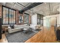 Bright living room with exposed brick, concrete ceiling, hardwood floors, and large windows at 1863 Wazee St # 4E, Denver, CO 80202