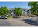 Wide angle view of a light blue townhome community with manicured lawns, trees, and nearby parking at 5255 Memphis St # 811, Denver, CO 80239