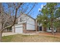 Side view of a two-story home with brick and siding and three-car garage, surrounded by mature trees at 10383 Erin Pl, Lone Tree, CO 80124