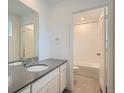 Bright bathroom featuring a gray vanity top, white cabinets and tile, and a combined shower and tub at 7357 S Yank Ct, Littleton, CO 80127