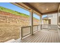 Covered outdoor patio features wood-look decking and white railing with a view of the backyard and retaining wall at 7357 S Yank Ct, Littleton, CO 80127