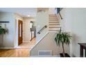 Welcoming foyer with hardwood floors, staircase, and views into the kitchen, creating an open and inviting space at 5886 Urban St, Arvada, CO 80004