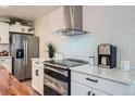Modern kitchen with stainless steel appliances, white cabinetry, quartz countertops, and a sleek stainless steel range hood at 5886 Urban St, Arvada, CO 80004