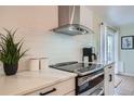 Bright kitchen featuring white cabinets, modern appliances, and a sleek stainless steel range hood at 5886 Urban St, Arvada, CO 80004