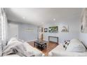 Cozy living room featuring hardwood floors, light gray walls, and white couches at 8438 Ames St, Arvada, CO 80003