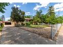 Exterior shot of a quaint home with a fenced front yard and mature trees at 10841 Montview Blvd, Aurora, CO 80010
