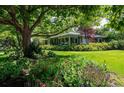 Well-manicured front yard with colorful flowers, a spacious lawn, and mature shade trees creating a serene setting at 990 S Jackson St, Denver, CO 80209