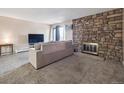 Cozy living room with stone fireplace, large window, and plush carpeting at 381 S Ames St # G101, Lakewood, CO 80226