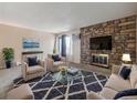 Living room featuring a stone fireplace, contemporary furniture, and large windows at 381 S Ames St # G101, Lakewood, CO 80226