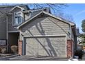 Attached two-car garage featuring painted siding, brick accents, and a well-maintained driveway at 7915 Flower St # D, Arvada, CO 80005