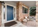 Inviting front porch with brick accents, seating, and a charming blue front door at 6041 S Salida Ct, Aurora, CO 80016