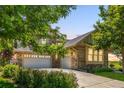 Lovely stone home featuring a three-car garage with an extended driveway and landscaping at 27565 E Nova Pl, Aurora, CO 80016