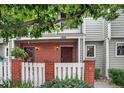 Inviting townhouse featuring a brick front, white picket fence, and manicured landscaping at 7474 E Arkansas Ave # 18-10, Denver, CO 80231