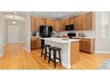 Well-lit kitchen featuring wood cabinets, a center island with seating, and modern black appliances at 6520 S Newcastle Way, Aurora, CO 80016