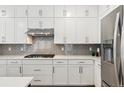 Kitchen with gray backsplash, white cabinets, and stainless steel hood at 17214 W 94Th Ave, Arvada, CO 80007