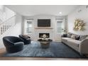 Bright living room featuring a cozy fireplace, stylish seating, a large area rug and hardwood flooring at 8028 Williams Fork Ave, Littleton, CO 80125