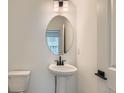 Chic powder room with pedestal sink, oval mirror, and modern fixtures at 1759 Peak Loop, Broomfield, CO 80023