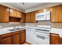Traditional kitchen featuring wood cabinets, white appliances, and neutral countertops at 745 S Alton Way # 9B, Denver, CO 80247