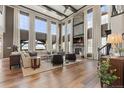 Light-filled living room with tall windows, stone fireplace, and hardwood floors at 10525 Sunshower Pl, Highlands Ranch, CO 80126