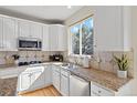 Well-lit kitchen with stainless steel appliances, white cabinets, granite counters, and a window overlooking the yard at 5686 Brook Hollow Dr, Broomfield, CO 80020
